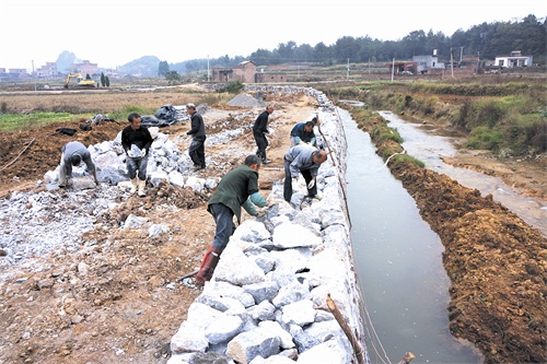 12月2日,寧遠縣保安鎮莊頭村建築工人正在砌護河堤.